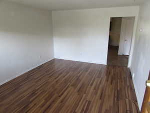 Empty room featuring dark wood finished floors and baseboards