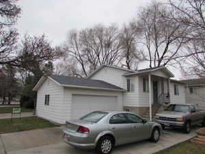 View of property exterior with a garage, a shingled roof, and driveway