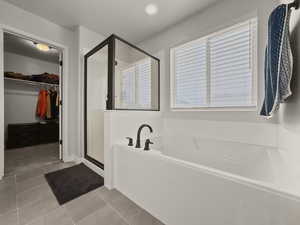 Bathroom featuring a walk in closet, a shower stall, a bath, light tile patterned floors, and recessed lighting