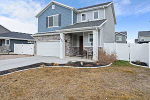 View of front facade featuring a gate, a garage, concrete driveway, stone siding, and covered porch