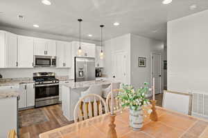 Kitchen featuring stainless steel appliances, white cabinets, a kitchen island, and wood finished floors