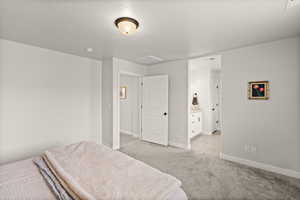 Bedroom featuring light colored carpet and connected bathroom