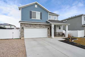 View of front of house with a gate, an attached garage, stone siding, driveway, and a porch