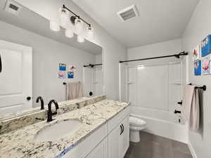 Bathroom featuring vanity, washtub / shower combination, and dark tile patterned flooring