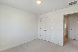 Unfurnished bedroom featuring carpet flooring, a closet, and a textured ceiling