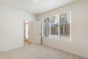 Unfurnished room with baseboards and light colored carpet