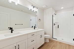 Full bathroom with a shower stall, double vanity, light wood-style floors, and recessed lighting