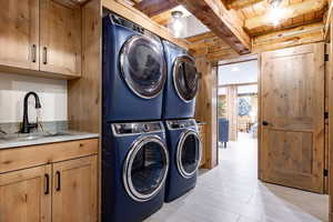 Laundry room featuring stacked washer / dryer, a wooden ceiling with exposed beams, and cabinet space