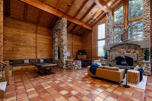 Living area with pool table, a high wood beamed ceiling, and rustic walls