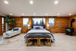 Bedroom with log walls, recessed lighting, and a wood stove