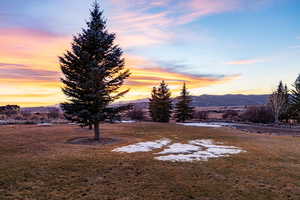 Yard at dusk with a mountain view and a yard
