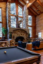 Playroom with a high wooden beamed ceiling, pool table, rustic walls, plenty of natural light, and a fireplace