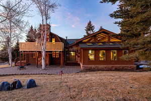 Back of property featuring a patio area, a gambrel roof, and stone siding
