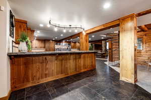 Kitchen with wood finish cabinets, log walls, dark stone countertops, recessed lighting, and a peninsula
