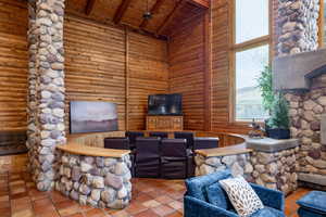 Living area with a fireplace, a high wood beamed ceiling, and log walls
