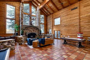 Living area featuring rustic walls, a high wood beamed ceiling, a stone fireplace, and billiards