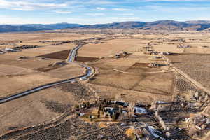 Aerial view of property and surrounding area featuring rural landscape and a mountain backdrop