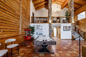 Playroom with rustic walls, a high wooden beamed ceiling, suspended lighting, and tile patterned flooring