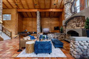Sunken living room with exterior fireplace, wooden walls, and a high wooden beamed ceiling