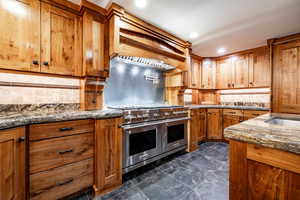 Kitchen featuring range with two ovens, dark stone counters, wood finish cabinetry, backsplash, and recessed lighting
