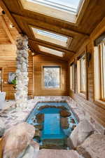 Detailed view of a hot tub, log walls, a wood ceiling with exposed beams, and a swimming pool