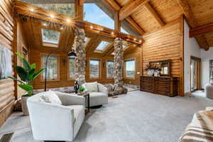 Living room featuring a high wooden beamed ceiling, carpet floors, a skylight, rustic walls, and a baseboard heating unit