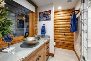 Bathroom featuring vanity, log walls, a shower, and recessed lighting