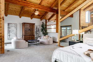 Carpeted bedroom with a high wood beamed ceiling and log walls