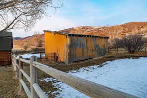 Snow covered structure featuring a mountain view and a pole building