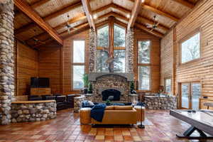 Tiled living area with ceiling fan, a high wood beamed ceiling, plenty of natural light, rustic walls, and french doors