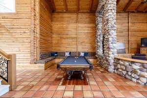 Recreation room featuring pool table, rustic walls, and a wood ceiling with exposed beams