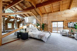 Bedroom featuring a high wooden beamed ceiling, multiple windows, carpet floors, rustic walls, and access to outside