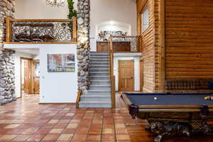 Rec room featuring a high ceiling, billiards table, rustic walls, and tile patterned floors