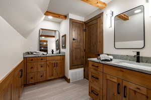 Full bath featuring two vanities, beam ceiling, recessed lighting, a wainscoted wall, and wood finish floors