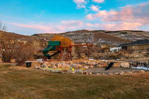 View of grassy yard with a mountain view and a playground