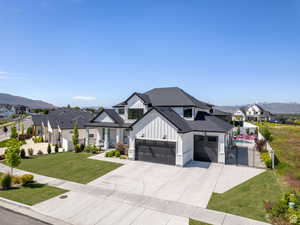 Modern farmhouse style home with board and batten siding, a residential view, a mountain view, roof with shingles, and driveway