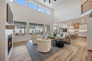 Living area with a fireplace, light wood-style floors, plenty of natural light, recessed lighting, and a ceiling fan