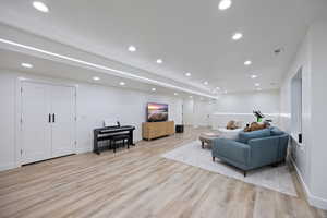 Living room with light wood-type flooring and recessed lighting