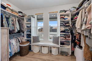 Walk in closet with light wood finished floors