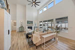 Living room with ceiling fan, light wood-type flooring, a fireplace, plenty of natural light, and recessed lighting