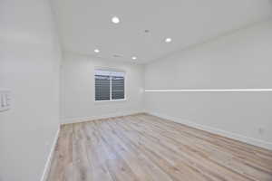 Empty room featuring light wood-style flooring and recessed lighting