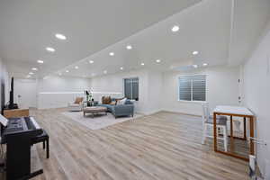 Living room with light wood-type flooring and recessed lighting