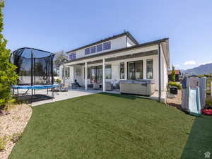 Rear view of house featuring a trampoline, a patio, a hot tub, a mountain view, and stucco siding