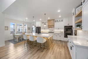 Two tone kitchen with a kitchen island with sink, a kitchen breakfast bar, stainless steel appliances, backsplash, and two tone cabinets