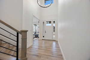 Entrance foyer featuring a high ceiling, light wood finished floors, and a chandelier