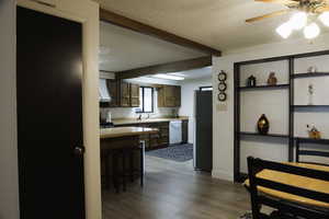 Kitchen featuring wood finish cabinetry, light countertops, a kitchen breakfast bar, a ceiling fan, and freestanding refrigerator