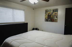 Bedroom with a textured ceiling and a ceiling fan