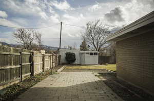 Fenced backyard featuring an outdoor structure and a patio area