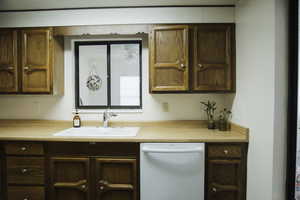 Kitchen featuring dishwasher, light countertops, and wood finish cabinetry