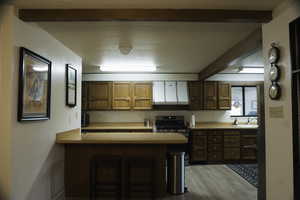 Kitchen with a breakfast bar area, wood finish cabinets, light countertops, a peninsula, and stainless steel appliances